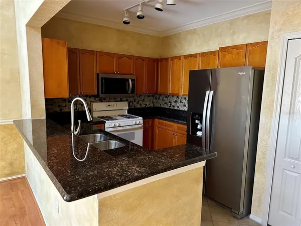 a kitchen with stainless steel appliances granite countertop a sink a microwave a refrigerator and a stove