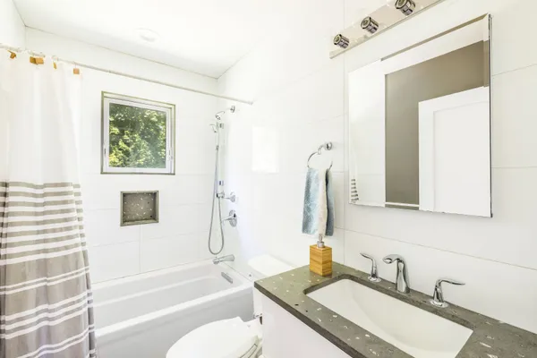 a bathroom with a granite countertop sink mirror toilet and bathtub