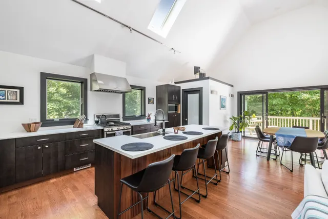 a dining hall with stainless steel appliances granite countertop a stove a sink a dining table and chairs with wooden floor