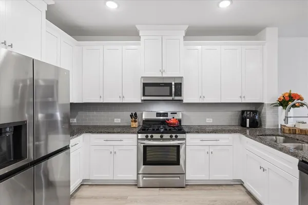 a kitchen with white cabinets and stainless steel appliances