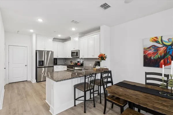 a kitchen with refrigerator and chairs