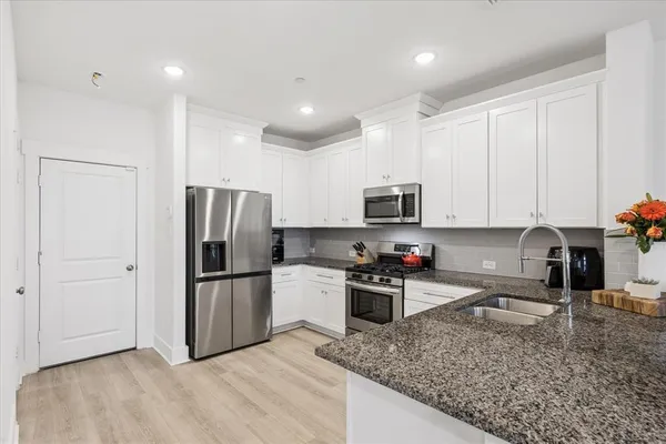 a kitchen with stainless steel appliances granite countertop a refrigerator sink and stove
