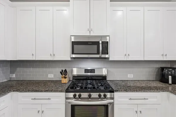 a kitchen with granite countertop white cabinets and stainless steel appliances