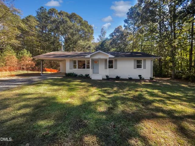 a view of a house with a big yard and large trees