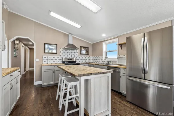 a kitchen with stainless steel appliances granite countertop a refrigerator a stove and a sink