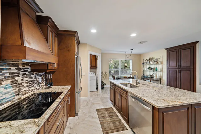 a kitchen with stainless steel appliances granite countertop a stove a sink and a refrigerator