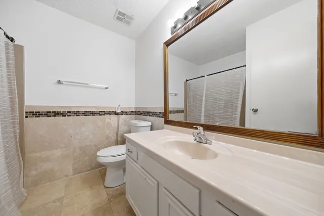 a bathroom with a granite countertop sink a toilet and a mirror