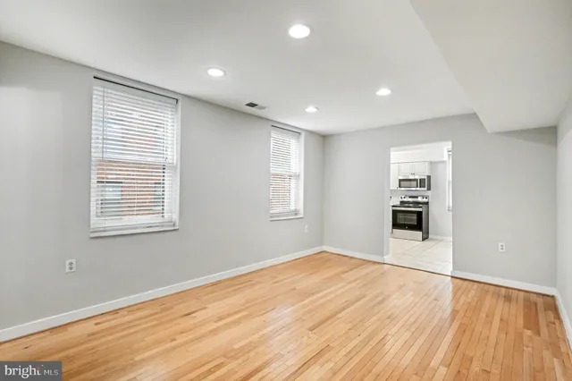 a view of empty room with wooden floor and fan