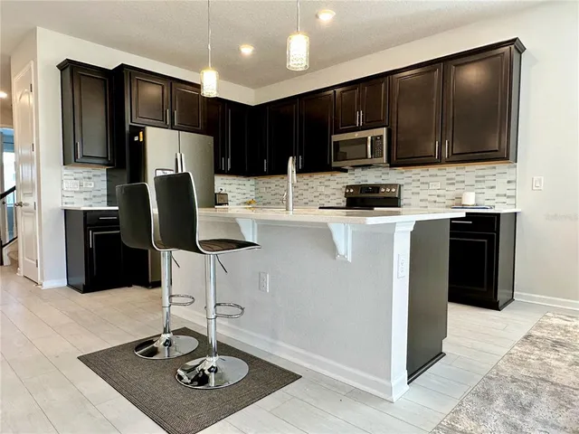 a kitchen with stainless steel appliances kitchen island granite countertop a refrigerator a stove a sink and a microwave