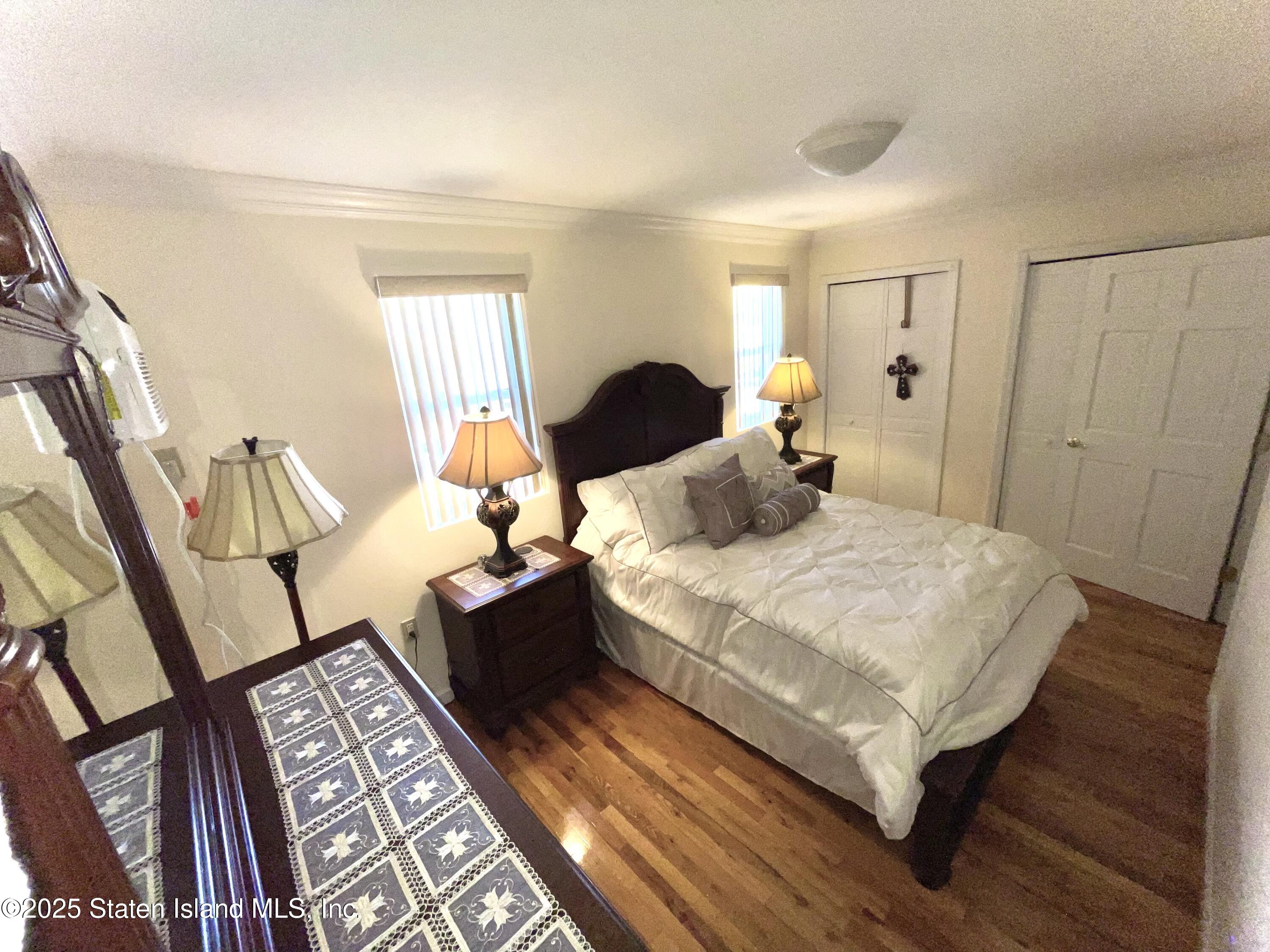 10 Token Street Staten Island, NY 10312 - Photo 26 of 39 a bedroom with a bed lamp and wooden floor