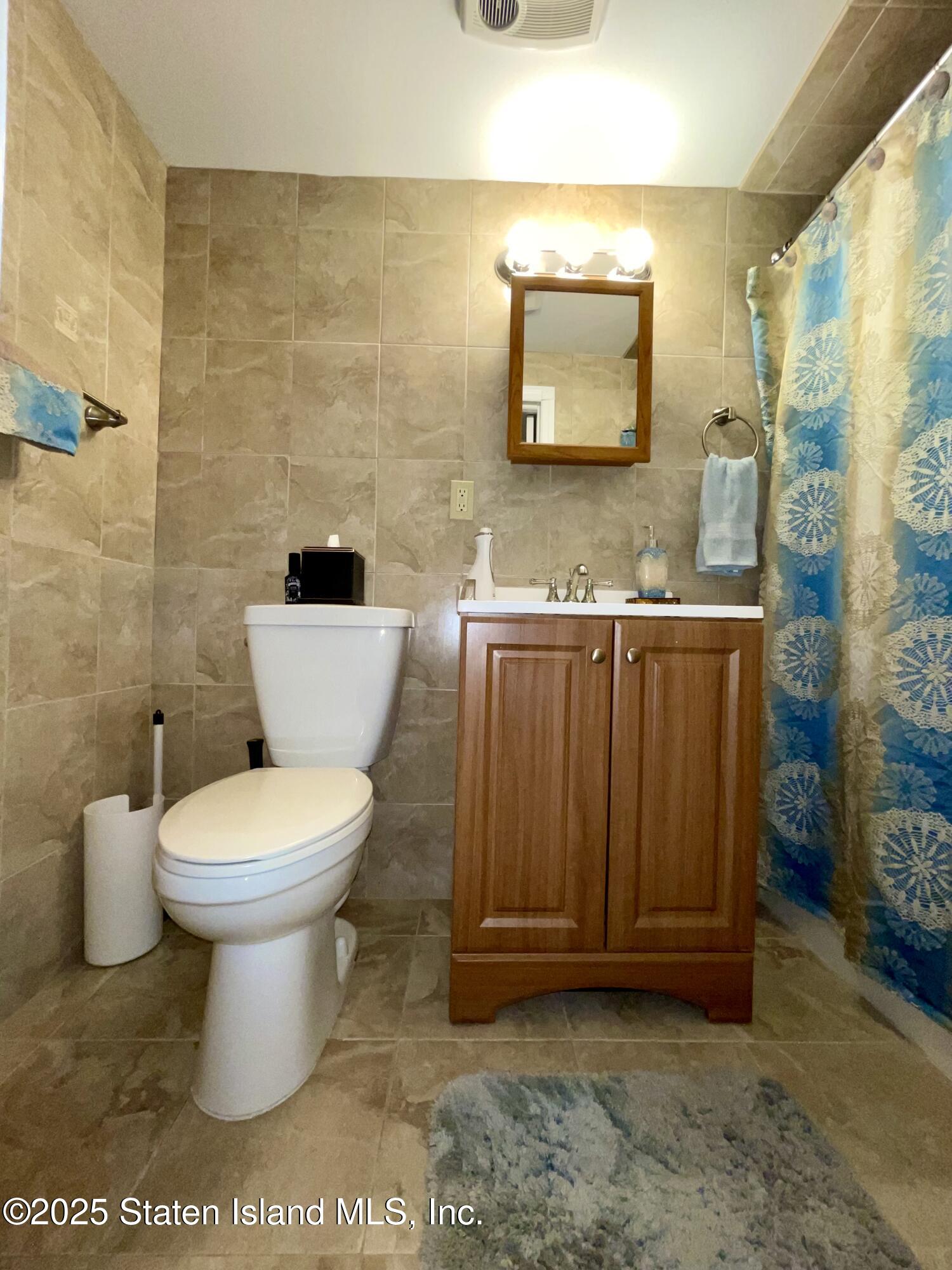 10 Token Street Staten Island, NY 10312 - Photo 37 of 39 a bathroom with a toilet a sink and mirror