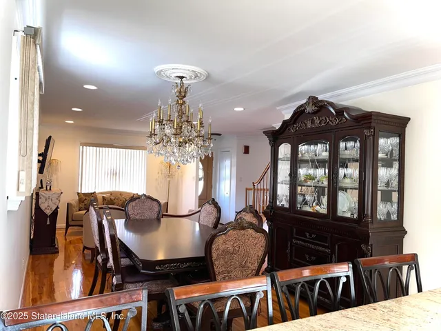 a living room with furniture a chandelier a large window and wooden floor