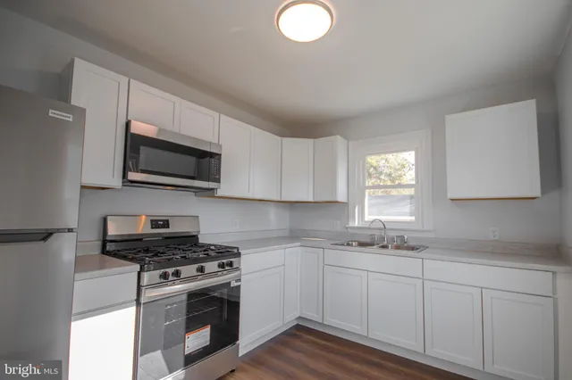 a kitchen with stainless steel appliances granite countertop a sink a stove top oven a chimney and cabinets