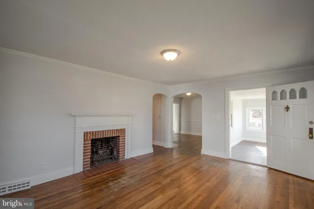 a view of an empty room with wooden floor and a fireplace