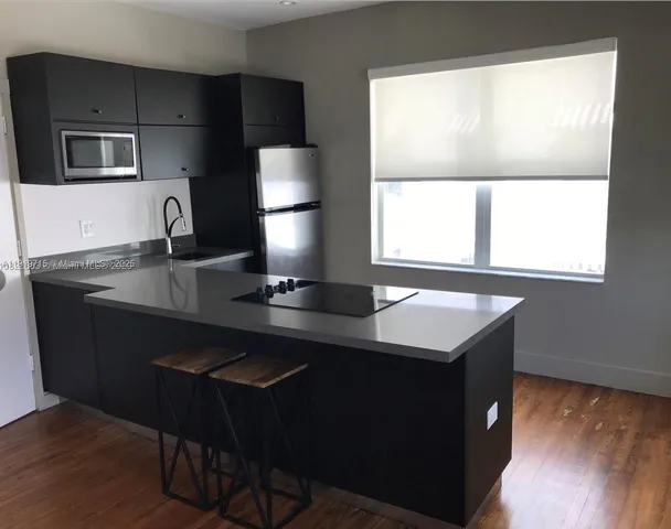 a kitchen with a sink a window and chairs