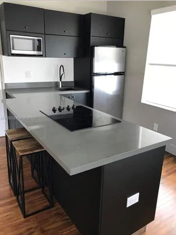 a kitchen with stainless steel appliances a refrigerator sink and wooden floor