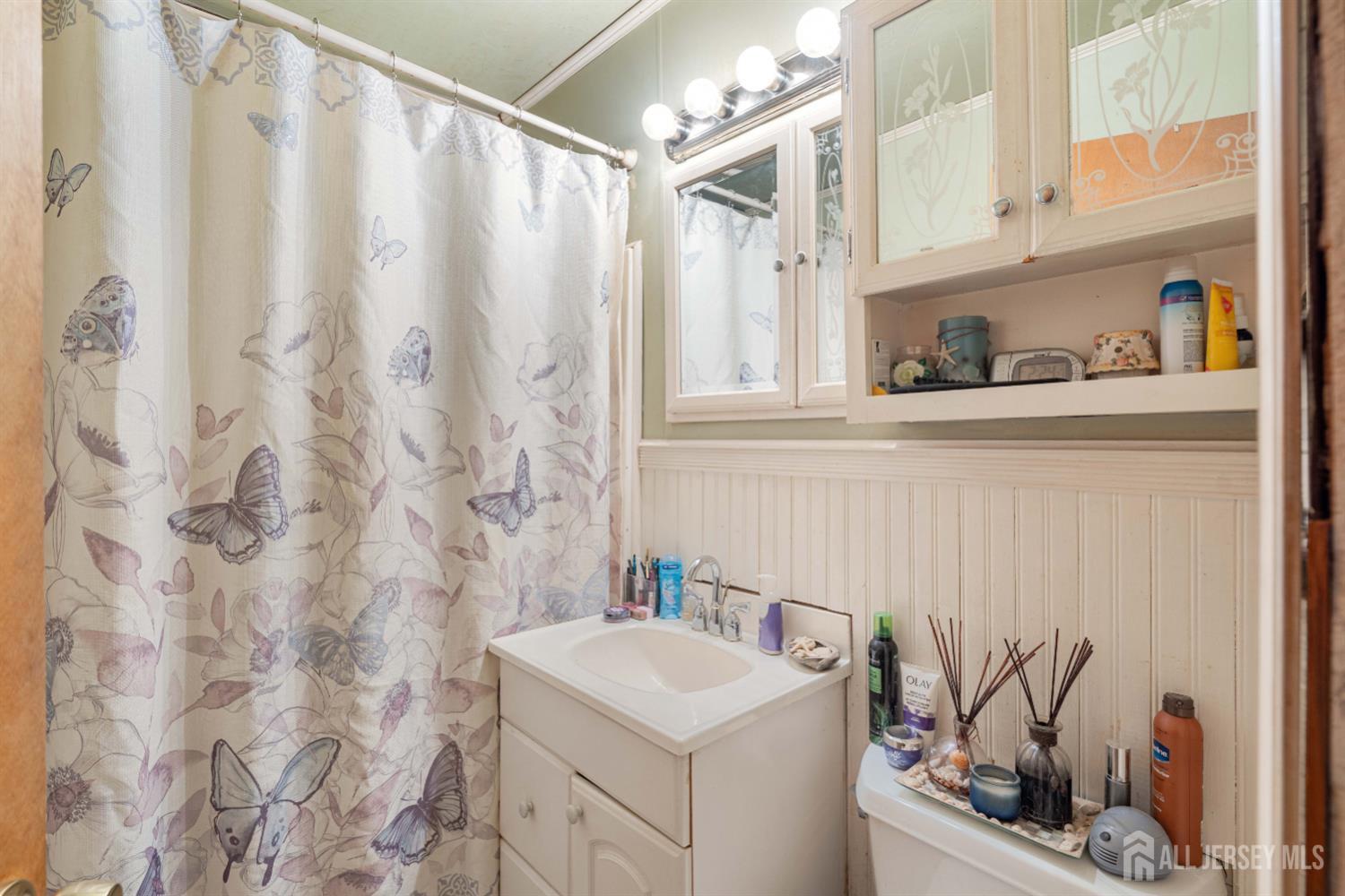 81 Larch Street Port Reading, NJ 07064 - Photo 11 of 25 a bathroom with a sink a vanity and a shower curtain