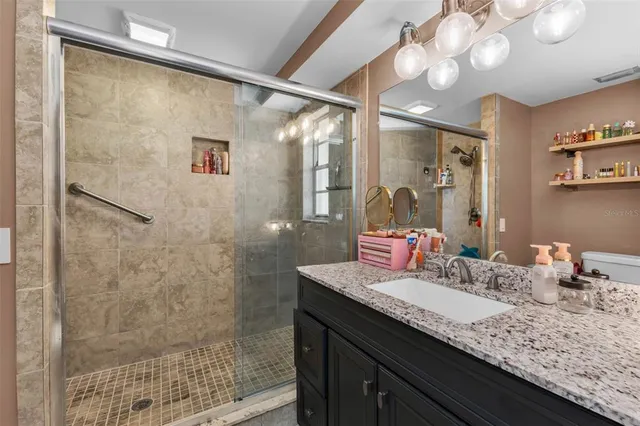 a bathroom with a granite countertop sink a large mirror and shower