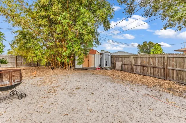 a view of backyard with wooden fence and large trees