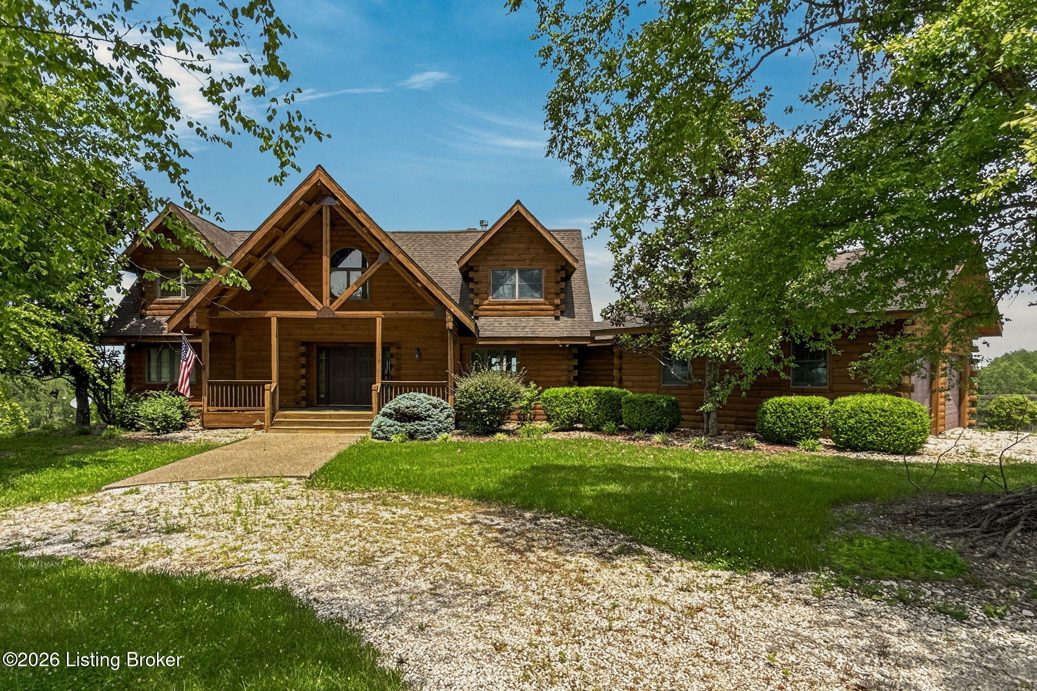 771 Mud Splash Road Elizabethtown, KY 42701 - Photo 17 of 85 Front elevation showcasing log siding, multiple dormers, timber entry framing, covered porch, and established landscaping with mature trees and manicured shrubs