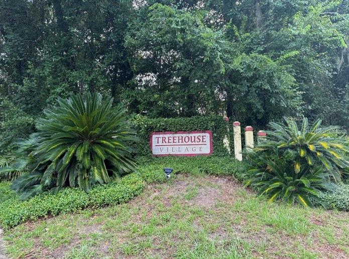 a sign that is sitting in a backyard of a house