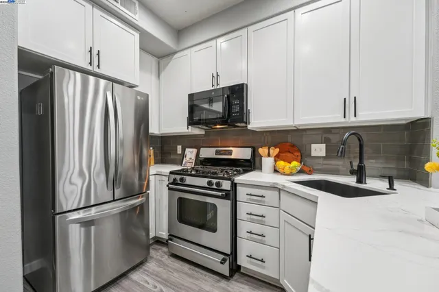 a kitchen with stainless steel appliances granite countertop a refrigerator sink and stove
