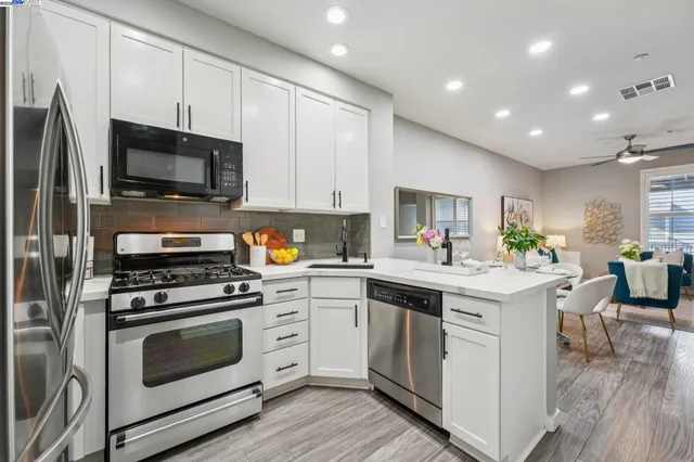 a kitchen with cabinets stainless steel appliances and wooden floor