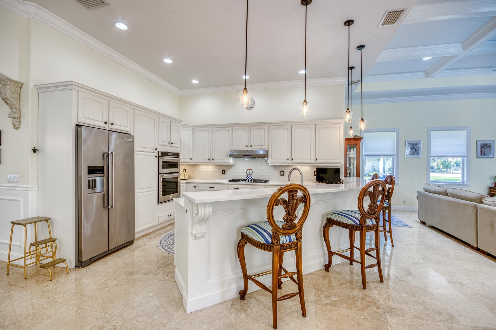 412 Meadowlark Drive Jupiter, FL 33458 - Photo 6 of 40 a kitchen with stainless steel appliances a table chairs refrigerator and microwave