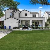 a view of a white house with a big yard and potted plants