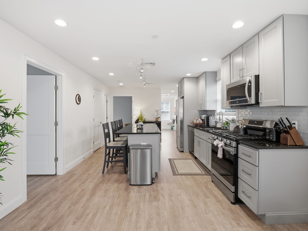 149 Pleasant Street, Unit 2 Marblehead, MA 01945 - Photo 12 of 41 a kitchen with stainless steel appliances granite countertop a stove top oven a sink dishwasher a refrigerator and white cabinets with wooden floor