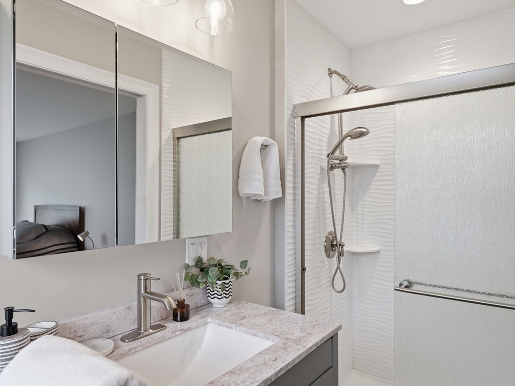 149 Pleasant Street, Unit 2 Marblehead, MA 01945 - Photo 28 of 41 a bathroom with a granite countertop sink a mirror and shower