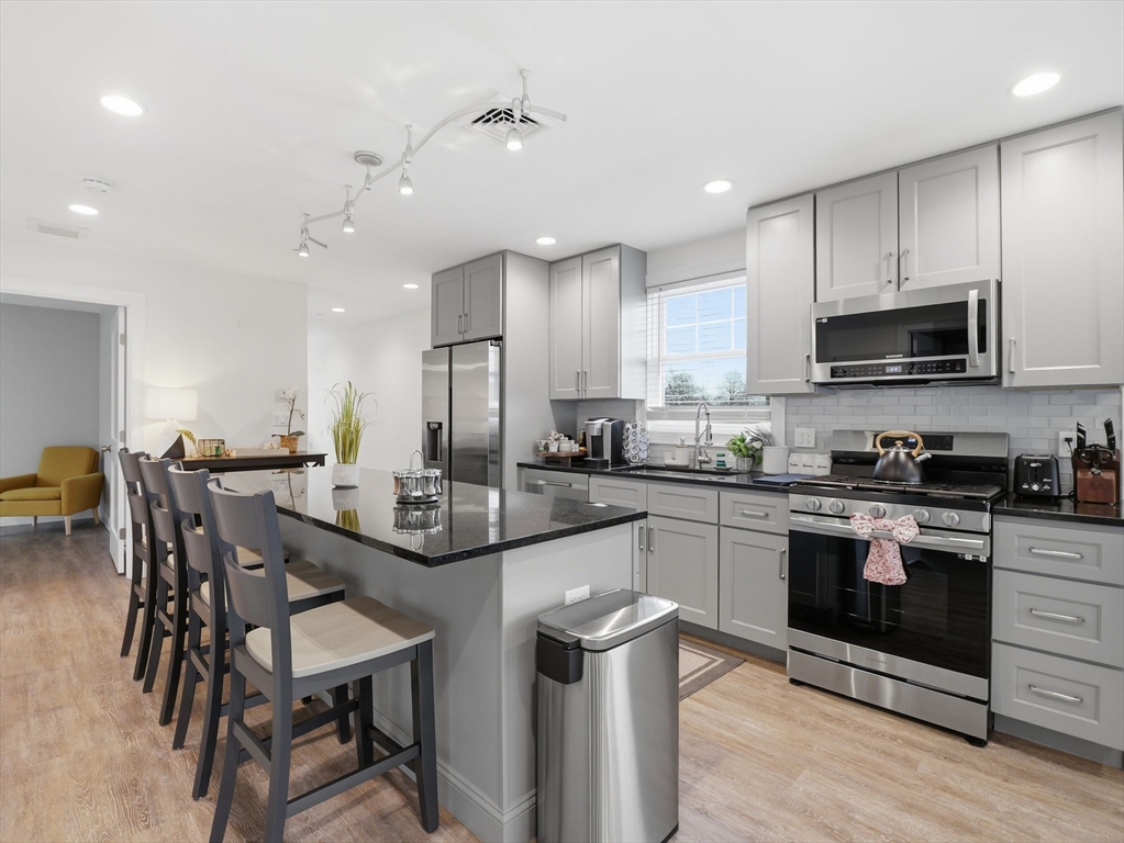 149 Pleasant Street, Unit 2 Marblehead, MA 01945 - Photo 7 of 41 a kitchen with kitchen island granite countertop wooden cabinets and stainless steel appliances