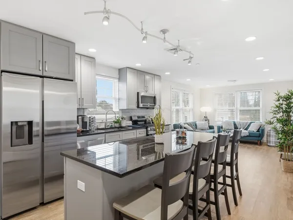 a kitchen with a dining table chairs wooden floor cabinets and stainless steel appliances