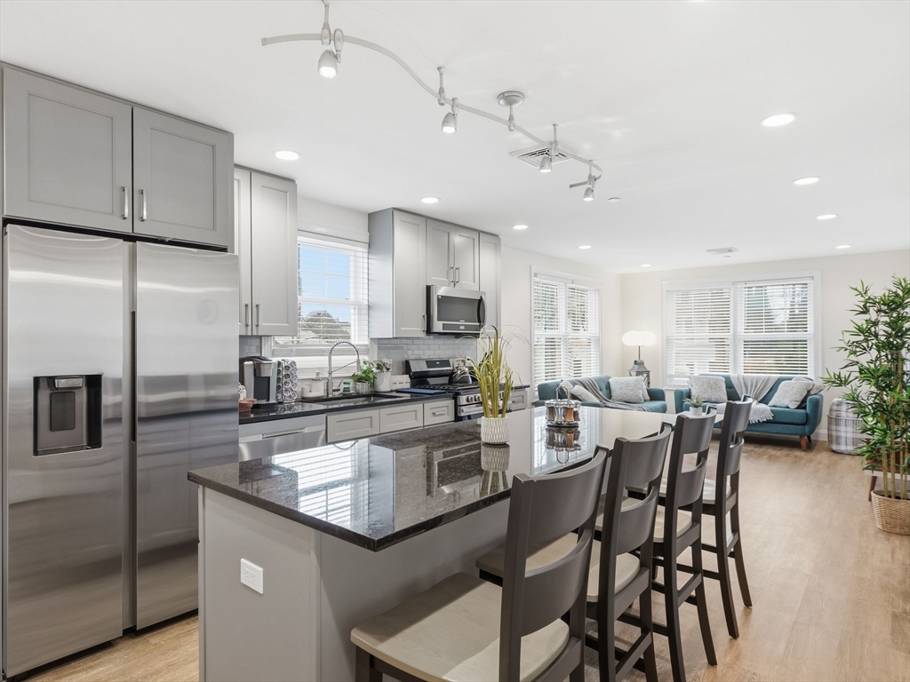 149 Pleasant Street, Unit 2 Marblehead, MA 01945 - Photo 8 of 41 a kitchen with a dining table chairs wooden floor cabinets and stainless steel appliances
