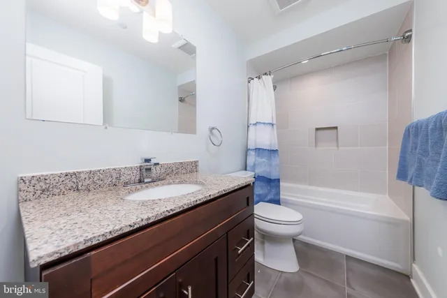 a bathroom with a granite countertop sink a toilet a mirror and shower