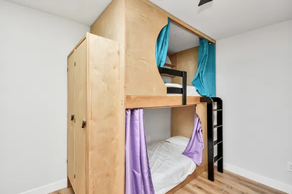 a view of a bedroom with wooden floor and windows