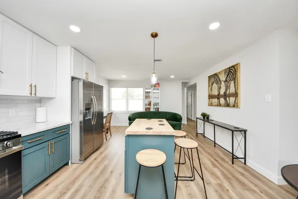 a kitchen with stainless steel appliances granite countertop a refrigerator a sink dishwasher a stove and a dining table with wooden floor