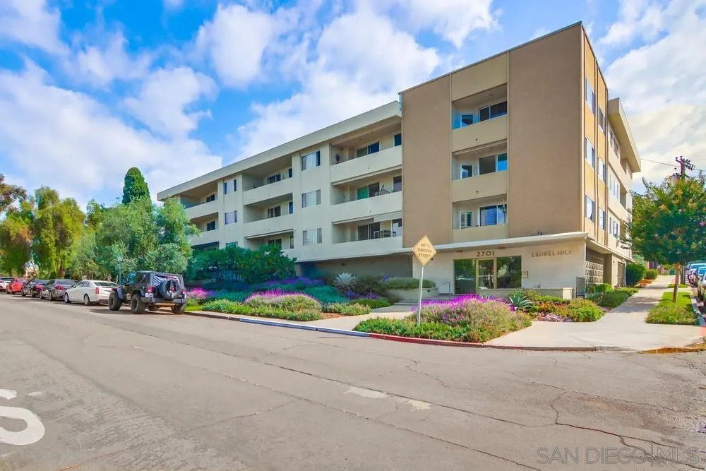 a front view of multi story residential apartment building with yard and flowers