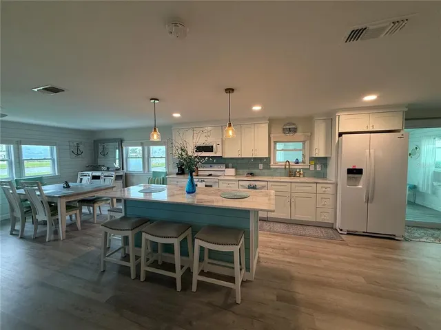 a kitchen with a dining table chairs refrigerator wooden floor and a window