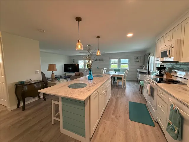 a large kitchen with kitchen island a stove a sink a dining table and chairs