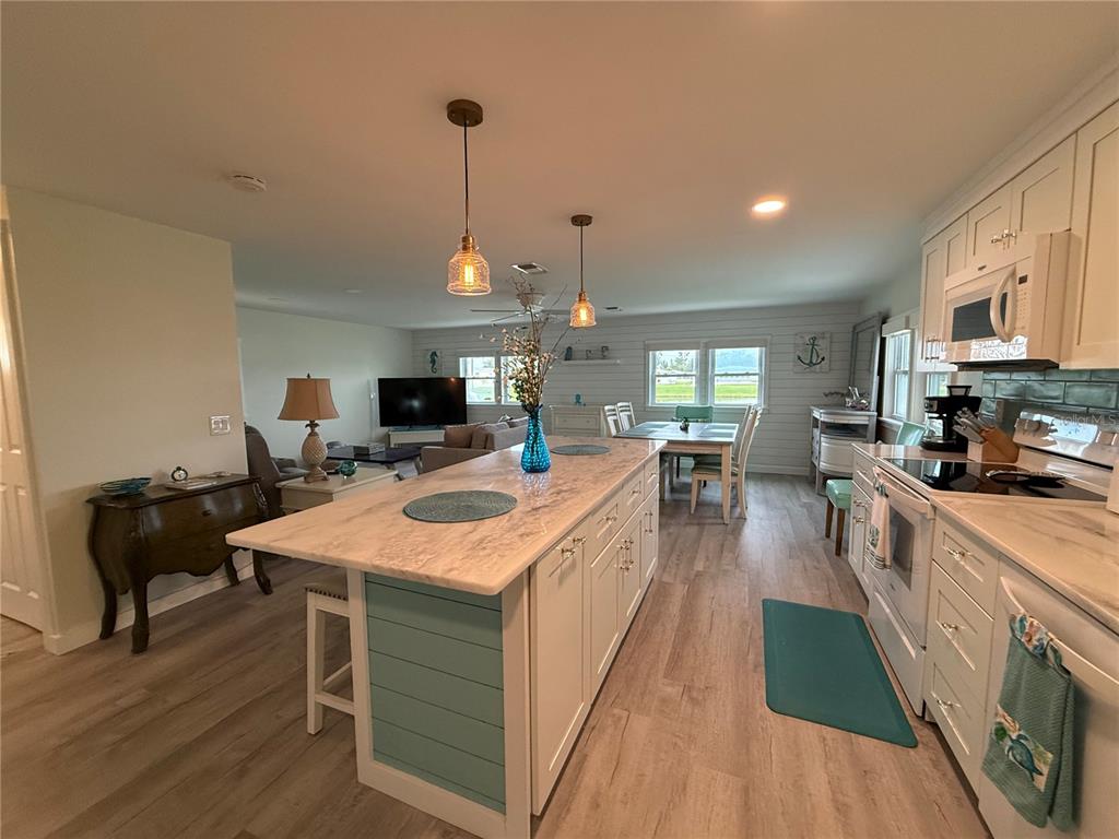 637 Los Altos, Unit 374 North Port, FL 34287 - Photo 5 of 26 a large kitchen with kitchen island a stove a sink a dining table and chairs