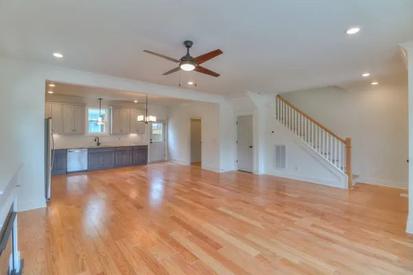 a view of an empty room with wooden floor and a ceiling fan