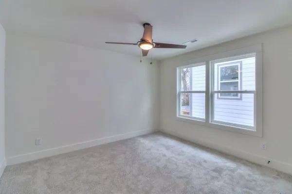 an empty room with windows and fan