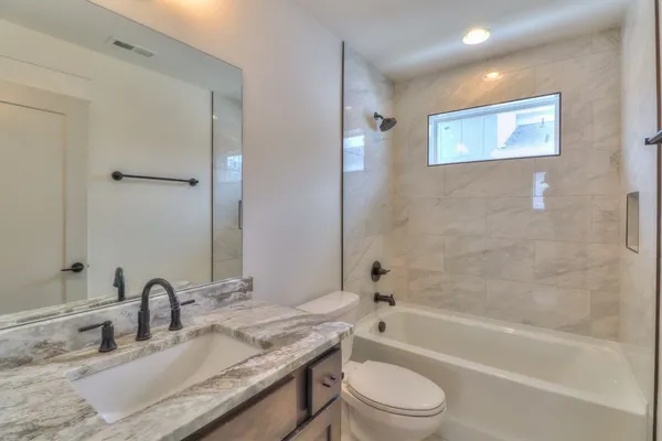 a bathroom with a granite countertop toilet a sink and a bathtub