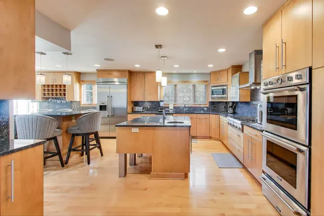 a large kitchen with stainless steel appliances granite countertop a stove top oven a sink dishwasher and white cabinets
