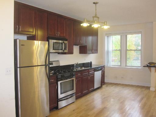 4540 West George Street, Unit 1 Chicago, IL 60641 - Photo 4 of 10 a kitchen with granite countertop a refrigerator stove top oven and cabinets