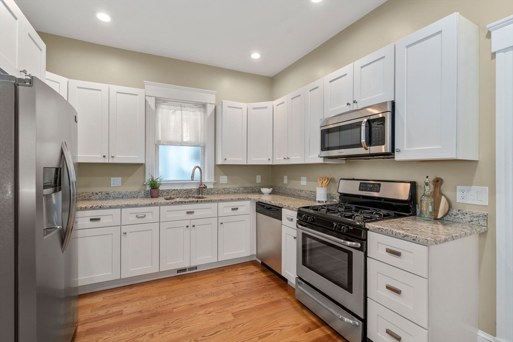 19 Pinckney Street, Unit 1 Somerville, MA 02145 - Photo 2 of 39 a kitchen with granite countertop white cabinets stainless steel appliances and a sink