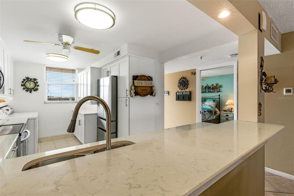 14900 Gulf Boulevard, Unit 410 Madeira Beach, FL 33708 - Photo 35 of 76 a kitchen with stainless steel appliances granite countertop a sink a stove cabinets and living room view
