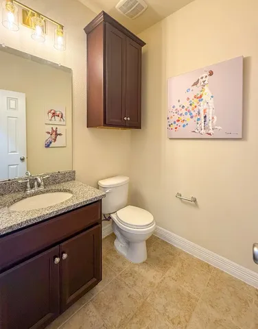 a bathroom with a granite countertop toilet and a sink