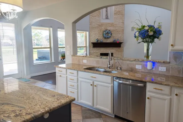 a kitchen with granite countertop a sink stainless steel appliances and cabinets